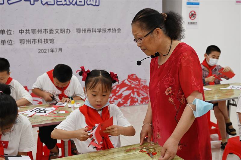2021年7月10日，鄂州市科協(xié)組織落駕坪小學(xué)學(xué)生在鄂州市科技館開(kāi)展社會(huì)主義核心價(jià)值觀系列活動(dòng)，圖為開(kāi)展的紅色剪影圓夢(mèng)中華剪紙活動(dòng)，老師指導(dǎo)同學(xué)剪紙.jpg